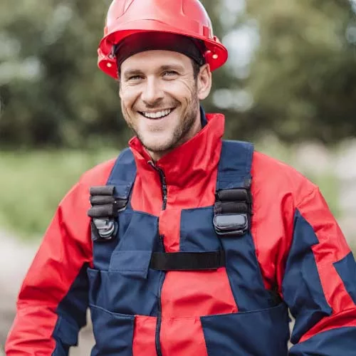 a man smiling wearing red and navy safety suit and red helmet